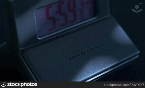 Close up of an alarm clock going off and a hand snoozing it