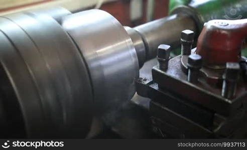 Close up of cutting tool processing on old lathe machine in workshop.