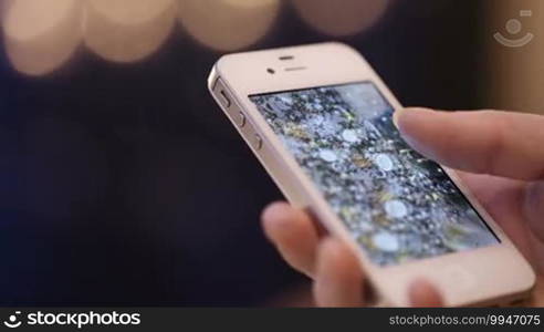 Close-up of female hands flipping through the photos on her smartphone.