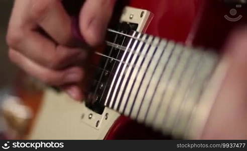 Close up of male musician playing electric guitar during jamming in recording studio.