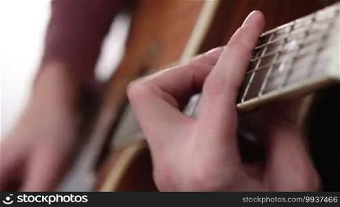 Close up of man's hand with mediator playing acoustic guitar. Guitarist setting chord on the guitar. Acoustic guitar with performer hands.