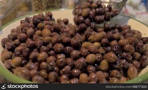 Close-up shot of a big bowl full of marinated olives at a food market