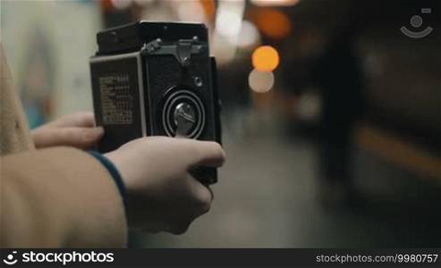 Close-up shot of a woman with a retro camera taking a photo or video of an approaching subway train. Focus on the camera