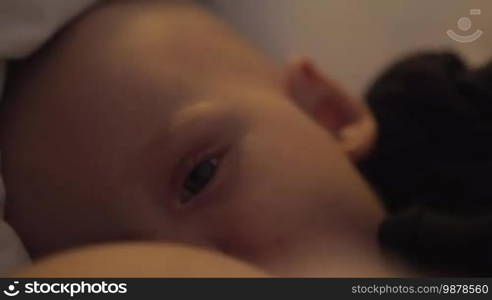 Close-up shot of breastfeeding sleepy baby girl of six months old