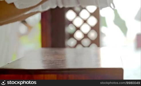 Close-up shot of female hands putting fresh white towels with pink flower on small table at beauty spa