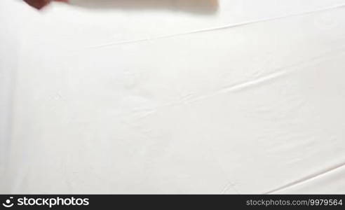 Close-up shot of female hands putting two white clean towels with olive branches on bed