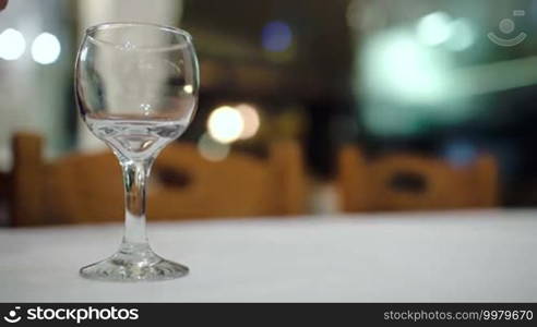 Close-up shot of pouring white wine into glass on the table in restaurant. Alcoholic drinks
