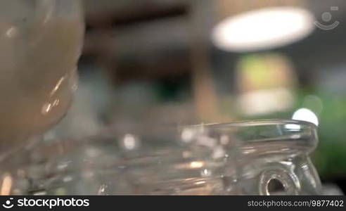 Close-up shot of serving masala tea in the restaurant. Pouring Indian hot drink into a glass tea bowl