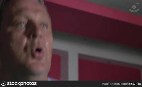 Close up shot of sweaty face of strong senior man running on treadmill in fitness center