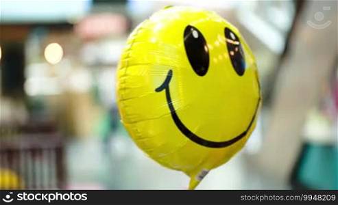 Close-up shot of yellow smiling balloon floating in the air