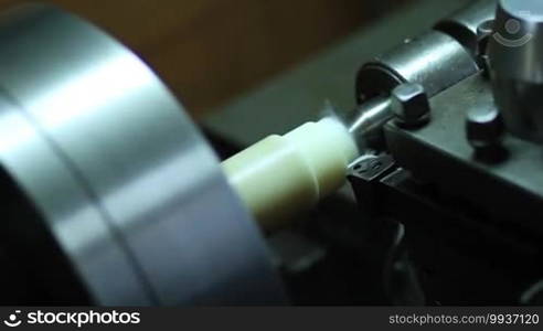 Close up turning lathe in action. Cutting workpiece processing on lathe machine in workshop. Selective focus on tool. Angle view.