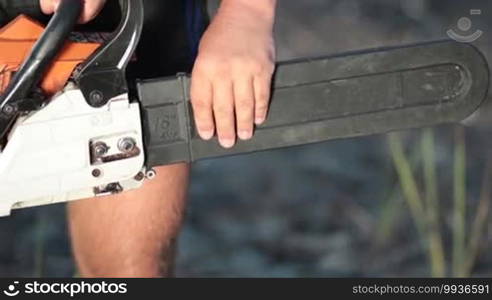 Close up view of man holding chainsaw and removing the protective housing