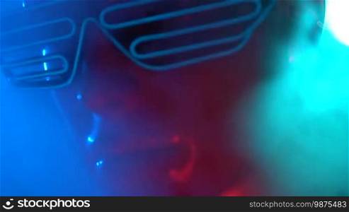 Closeup face of female mannequin in blue glowing LED glasses over dark smoky background