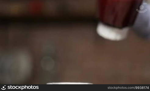 Closeup female hands pouring vegetable smoothie from blender shaker jug into mason jar in the kitchen at home. Focus on glass jar in woman's hand. Healthy eating and dieting.