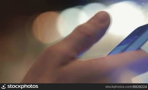 Closeup shot of a smartphone in a male hand. The man is texting to friends.