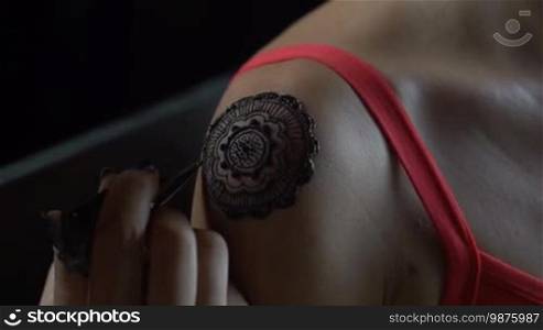 Closeup video of henna tattoo artist drawing on woman's shoulder - video in slow motion