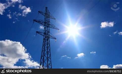Clouds, sky, and sun behind the electricity pylon