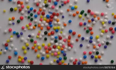 Colorful sprinkles sugar candy moving on white surface background