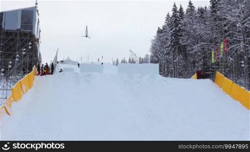 Competitions in freestyle aerial skiing. A professional aerialist performs double backflips and twists from a medium-sized ski jump. Good performance.