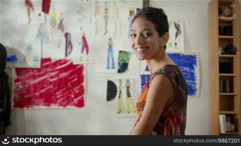 Confident and successful entrepreneur, portrait of happy Hispanic young woman working as a fashion designer and dressmaker in an atelier