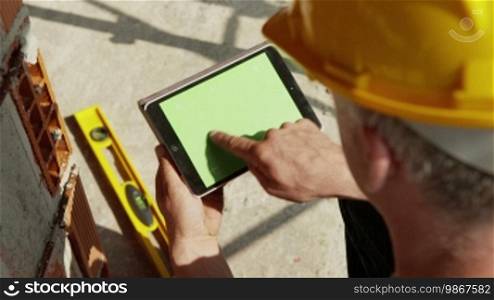 Construction worker and new building, adult man at work with safety helmet and using digital tablet computer for data entry. Part 8 of 8