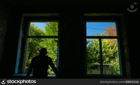 Contractor installing a new window in the house, bright trees and blue sky outside