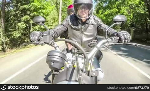 Couple bikers in a leather jacket riding a motorcycle on the road