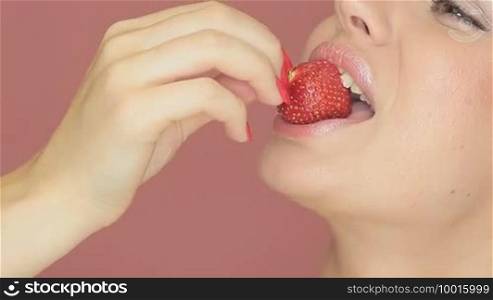 Cropped view portrait of the face of a beautiful woman with smiling eyes eating a strawberry