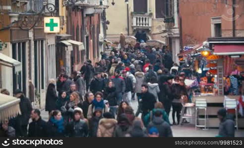 Crowded narrow street with outdoor cafe and pharmacy. Popular touristic destination widely known for its elegant decay