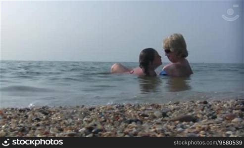 Daughter and mum lay joyful in sea water.