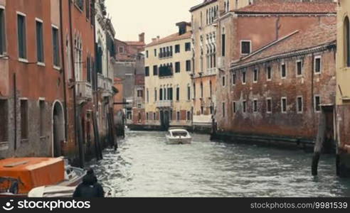 Different boats are moving along one of the water canals in Venice, Italy.