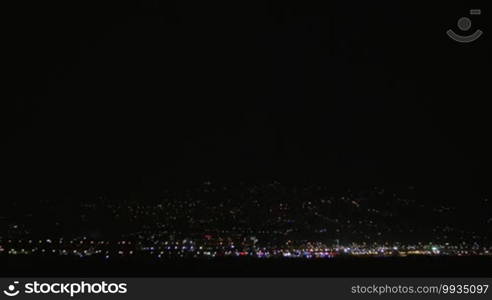 Distant city lights and lightning discharges in dark sky. Night thunderstorm