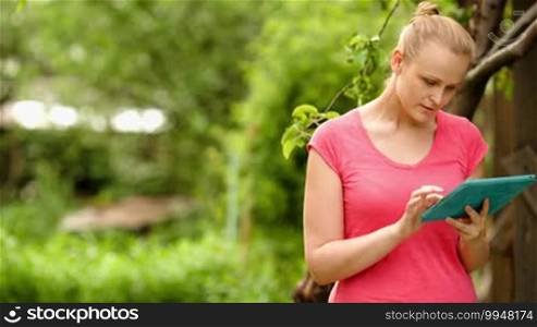 Dolly shot of a young woman typing on the touchpad outdoor