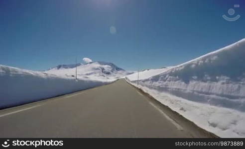 Driving a Car on a Mountain road in Norway with high snow wall