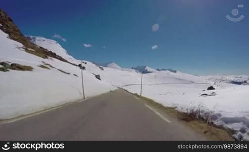 Driving a Car on a Mountain road in Norway with high snow wall