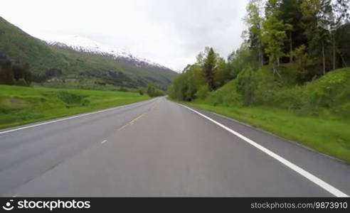 Driving a Car on a Mountain road in Norway with high snow wall