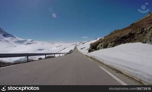 Driving a Car on a Mountain road in Norway with high snow wall