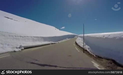 Driving a Car on a Mountain road in Norway with high snow wall