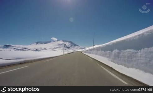 Driving a Car on a Mountain road in Norway with high snow wall