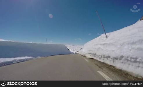 Driving a Car on a Mountain road in Norway with high snow wall