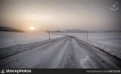 Driving in snow country with sunset on the horizon