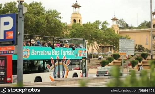 Ein Bus fährt in Barcelona, an bekannten Sehenswürdigkeiten (Vier Säulen, Museum) vorbei.