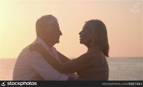 Elderly couple in love, honeymoon with old man and woman kissing near the sea at sunset. Sequence