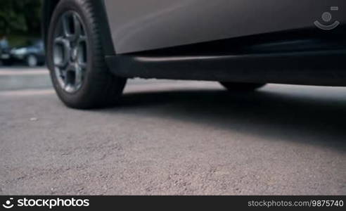 Elegant slim female legs in red high heels getting out of car in daylight. Low section. Dolly. Beautiful woman wearing high heel shoes stepping out of the car, parked on roadside.