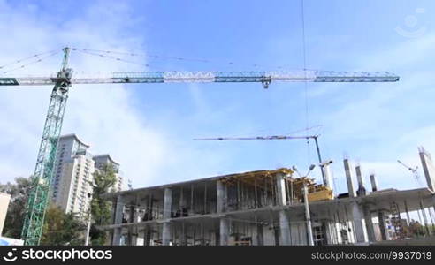 Elevating construction crane working against blue sky in fair weather