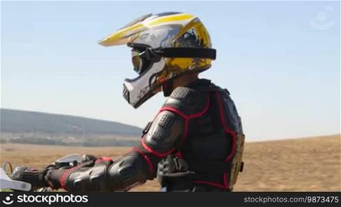 Enduro racer in motorcycle protective gear riding dirt bike vehicle shot side view closeup