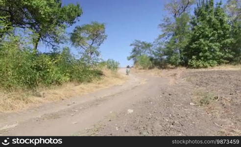 Enduro racer riding bike on dirt track tracking shot