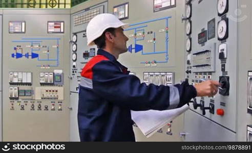 Engineer checks thermal sensors and writes into registry near main control panel of gas compressor station