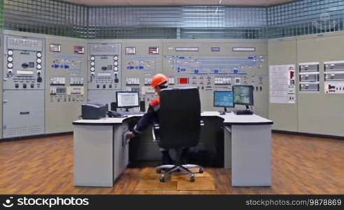 Engineer takes ruler out of drawer and makes some sketches near main control panel for gas compressor station, wide angle