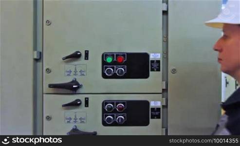 Engineer turns on electrical equipment from control panel, close-up